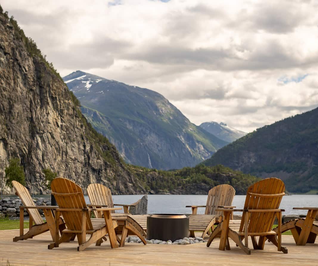 Trestoler rundt bålpanne med utsikt over fjorden og fjellene