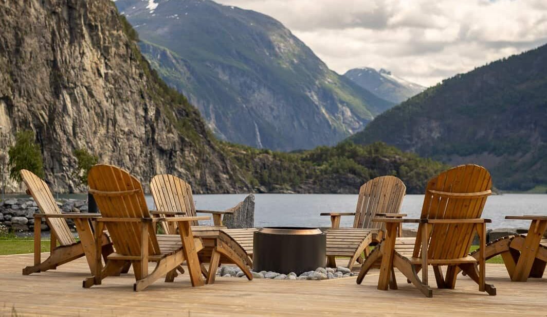 Trestoler rundt bålpanne med utsikt over fjorden og fjellene
