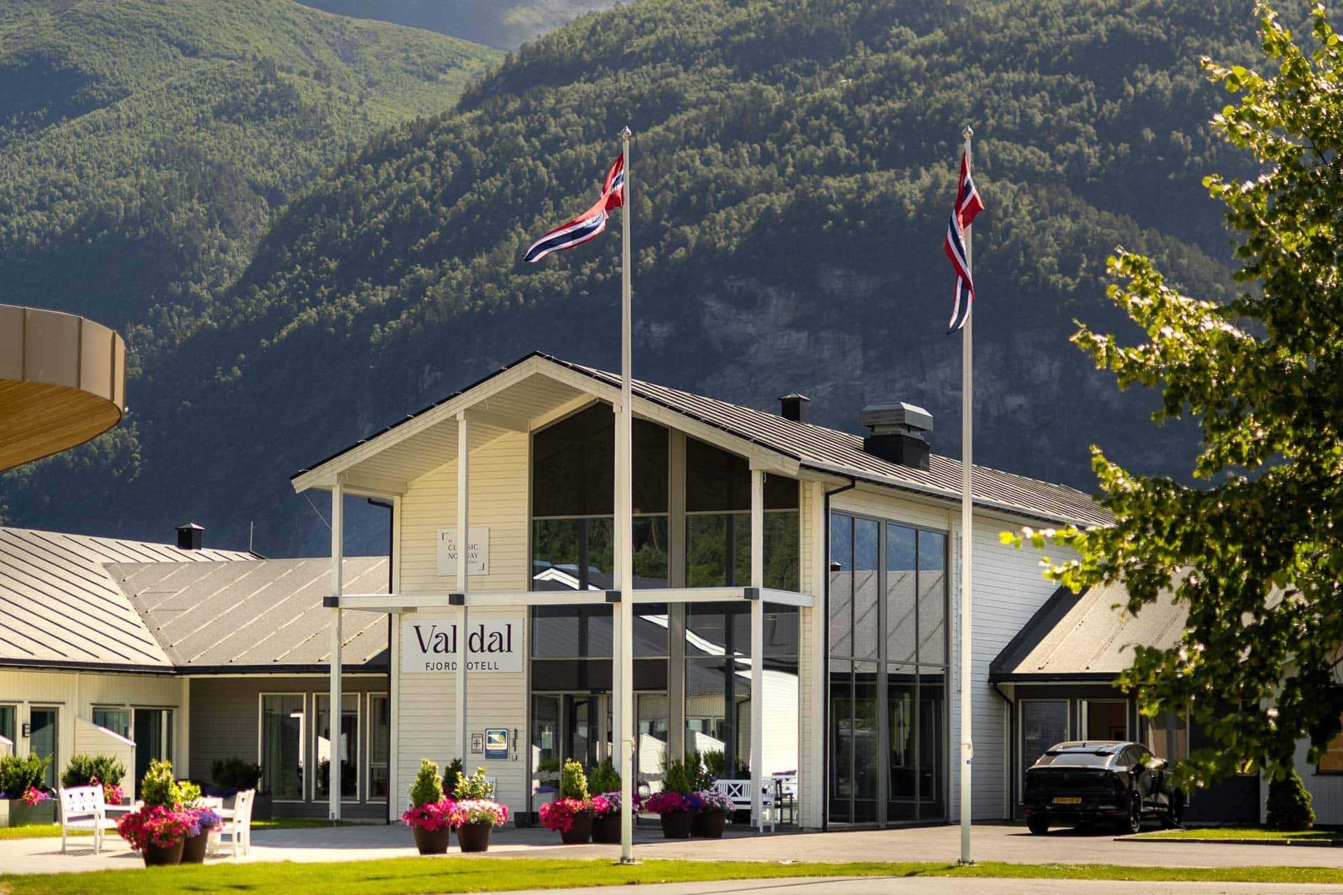 Valldal Fjordhotell med norske flagg og fjell i bakgrunnen